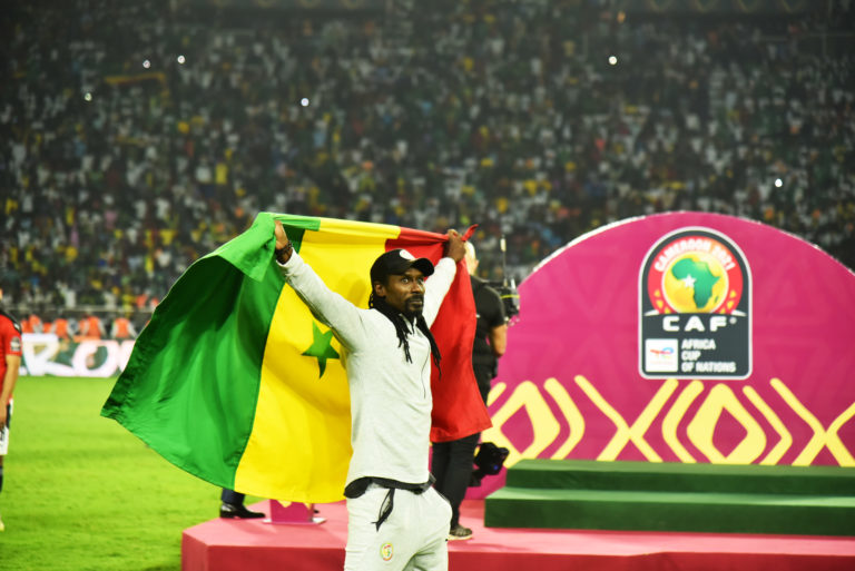 L'entraineur sénégalais célébrant la victoire de son équipe en brandissant le drapeau sénégalais